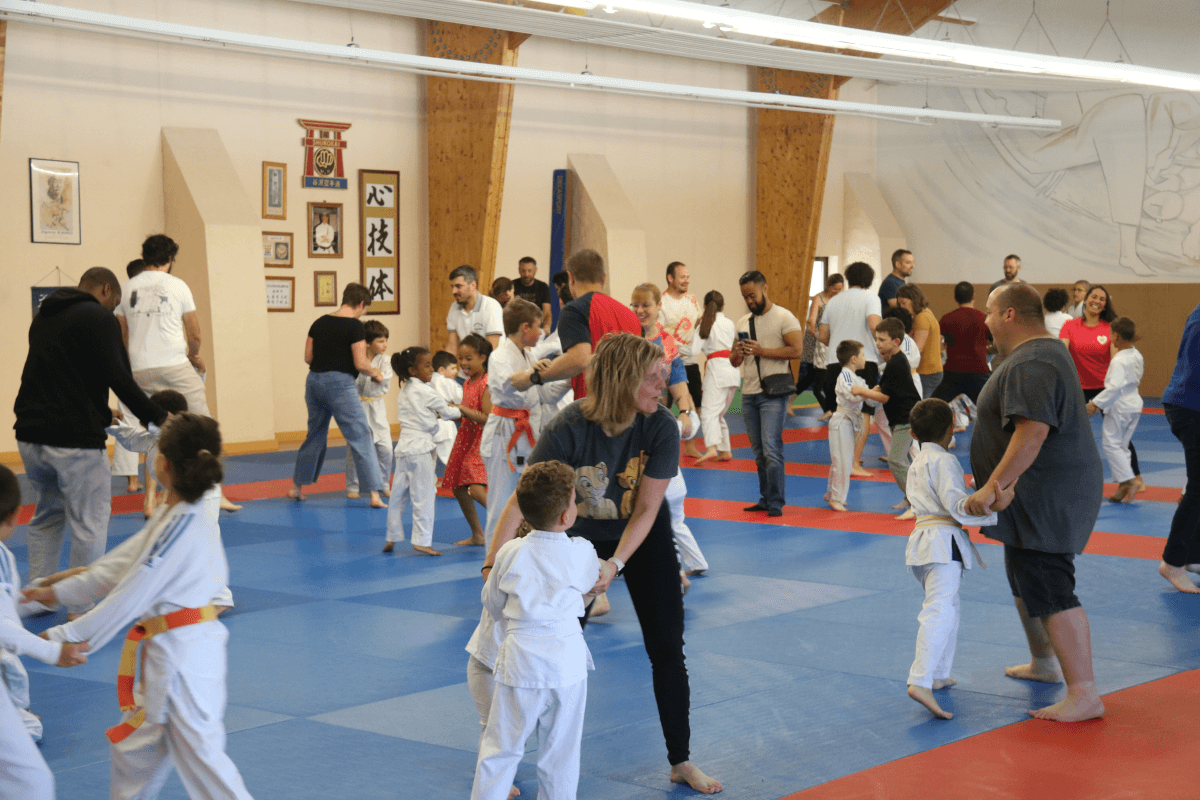 Un jeune judoka souriant recevant des instructions ou des félicitations d'un autre pratiquant plus expérimenté.