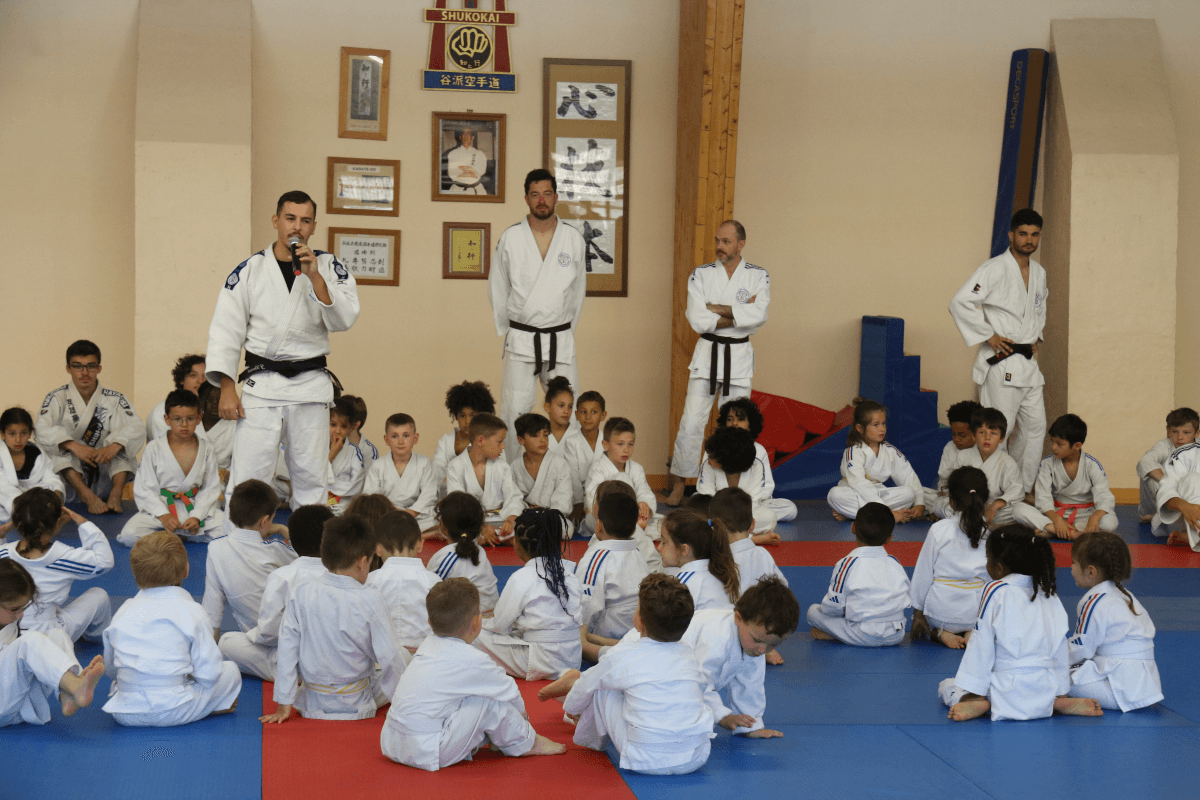 Groupe de judokas debout en ligne, tenant des trophées après une compétition ou un événement spécial au dojo.