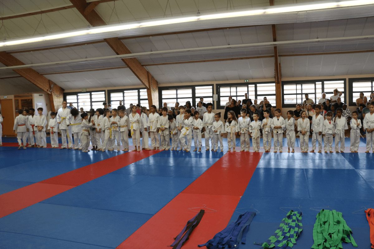 Photo de groupe réunissant tous les participants du dojo, jeunes et adultes, posant fièrement en tenue de judo.