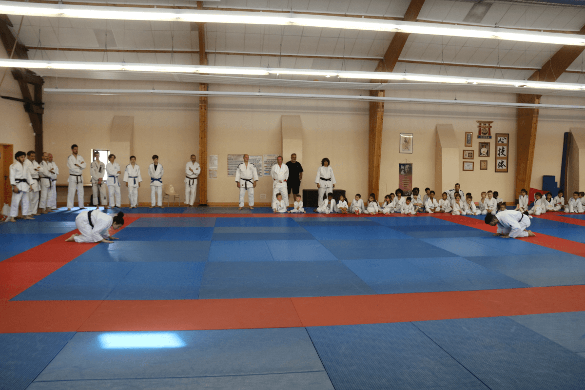 Grande photo de groupe du Dojo Family Day, avec des participants de tous âges et leurs familles, levant les mains en signe de célébration.