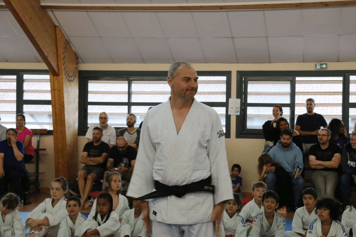 Un garçon regardant fièrement sa nouvelle ceinture de judo pendant une cérémonie de ceinture au dojo.