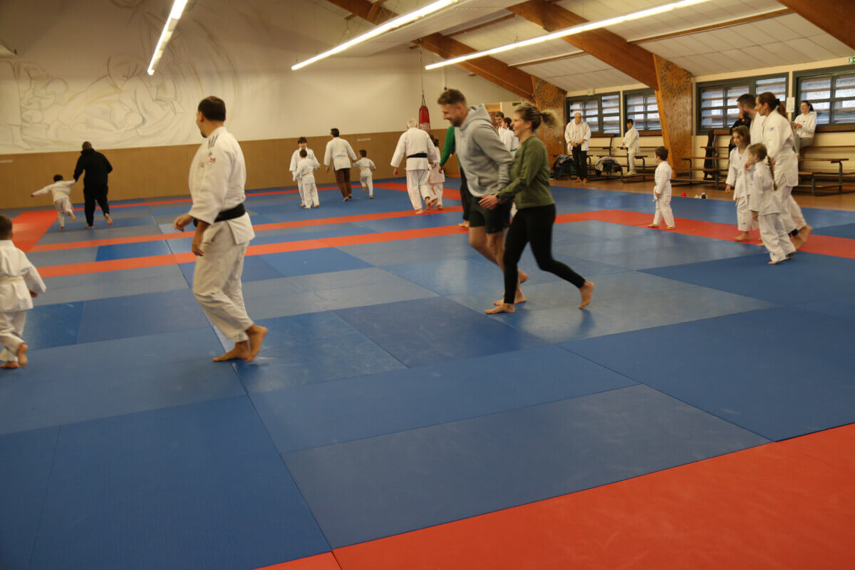 Un jeune judoka souriant recevant des instructions ou des félicitations d'un autre pratiquant plus expérimenté.