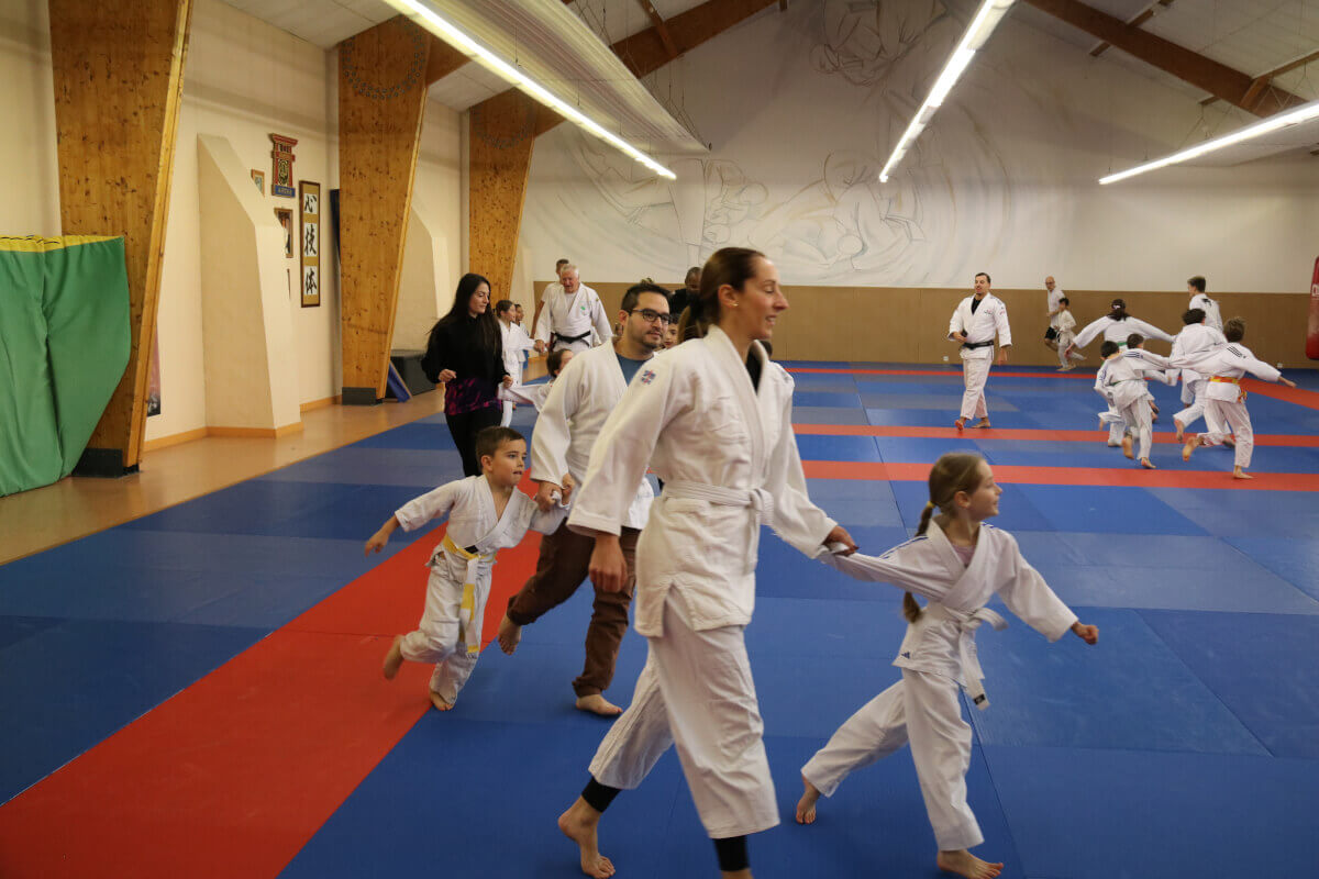 Groupe de judokas debout en ligne, tenant des trophées après une compétition ou un événement spécial au dojo.