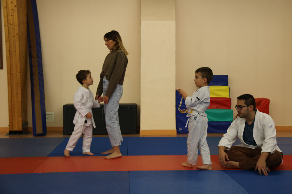 Grande photo de groupe du Dojo Family Day, avec des participants de tous âges et leurs familles, levant les mains en signe de célébration.