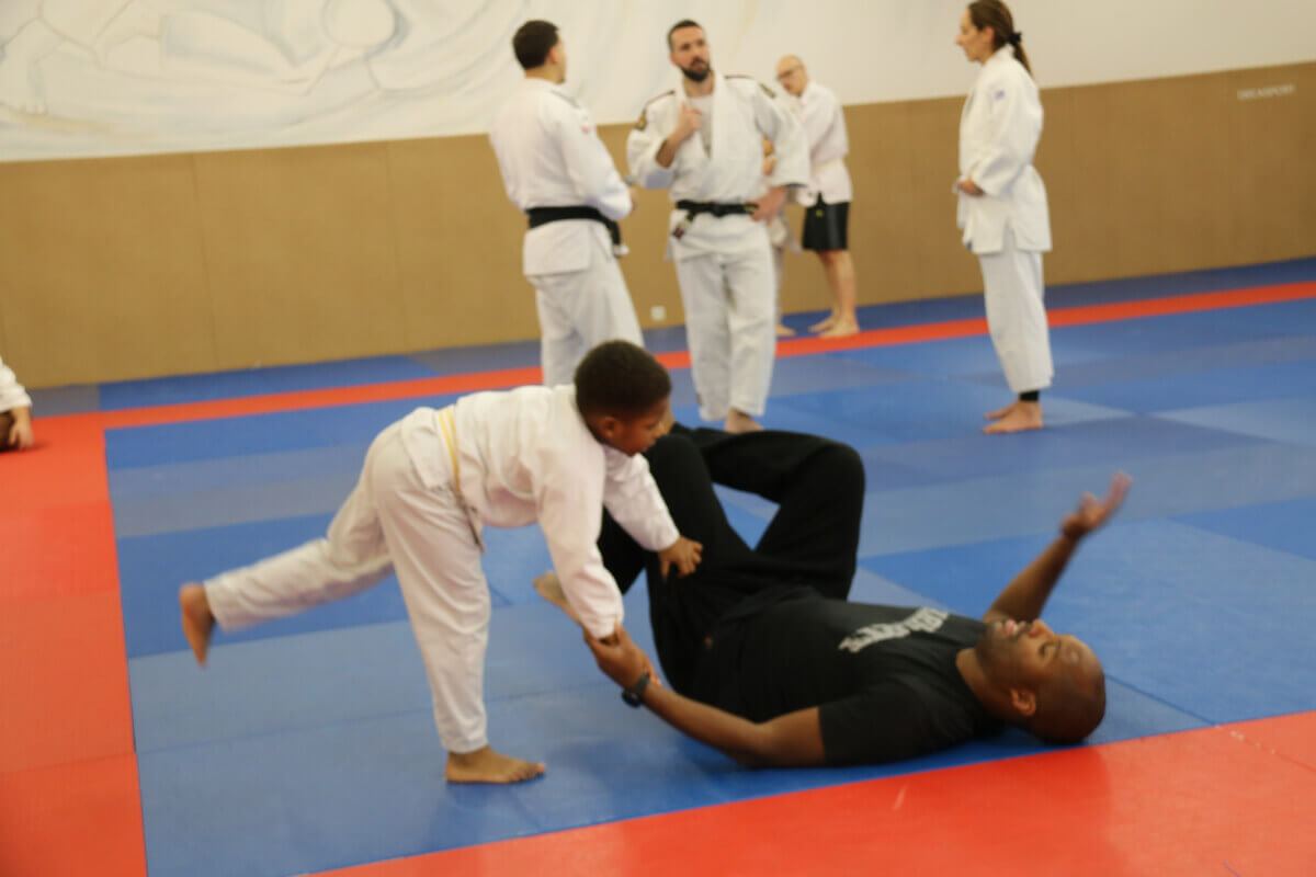 Un garçon regardant fièrement sa nouvelle ceinture de judo pendant une cérémonie de ceinture au dojo.