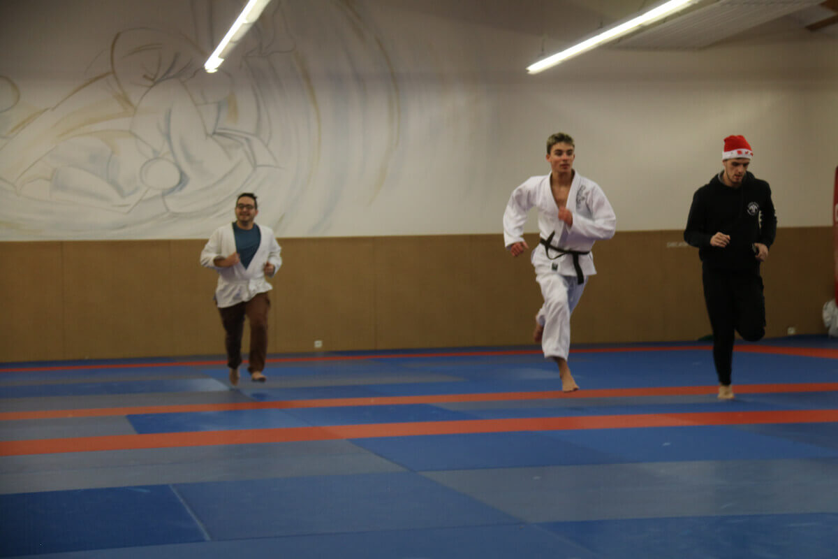 Un jeune judoka se préparant à recevoir sa nouvelle ceinture lors d'une cérémonie en présence de ses camarades et des parents.