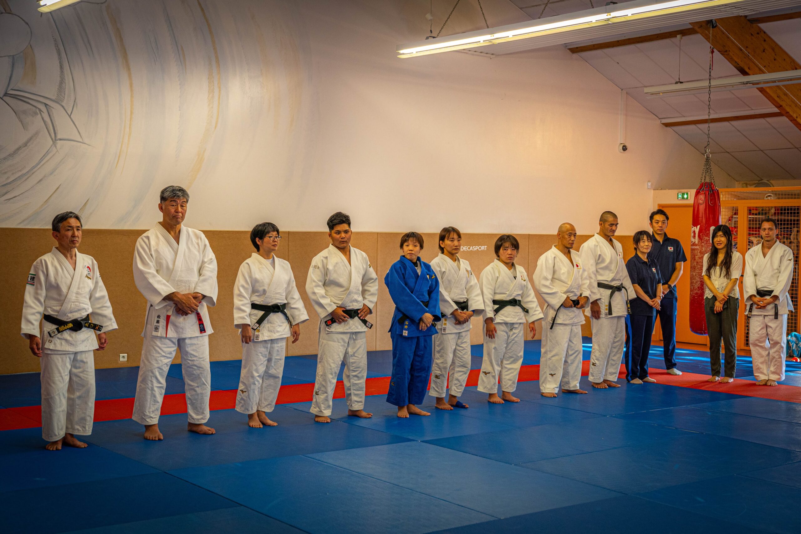 Groupe de judokas alignés avant un entraînement dans le dojo.