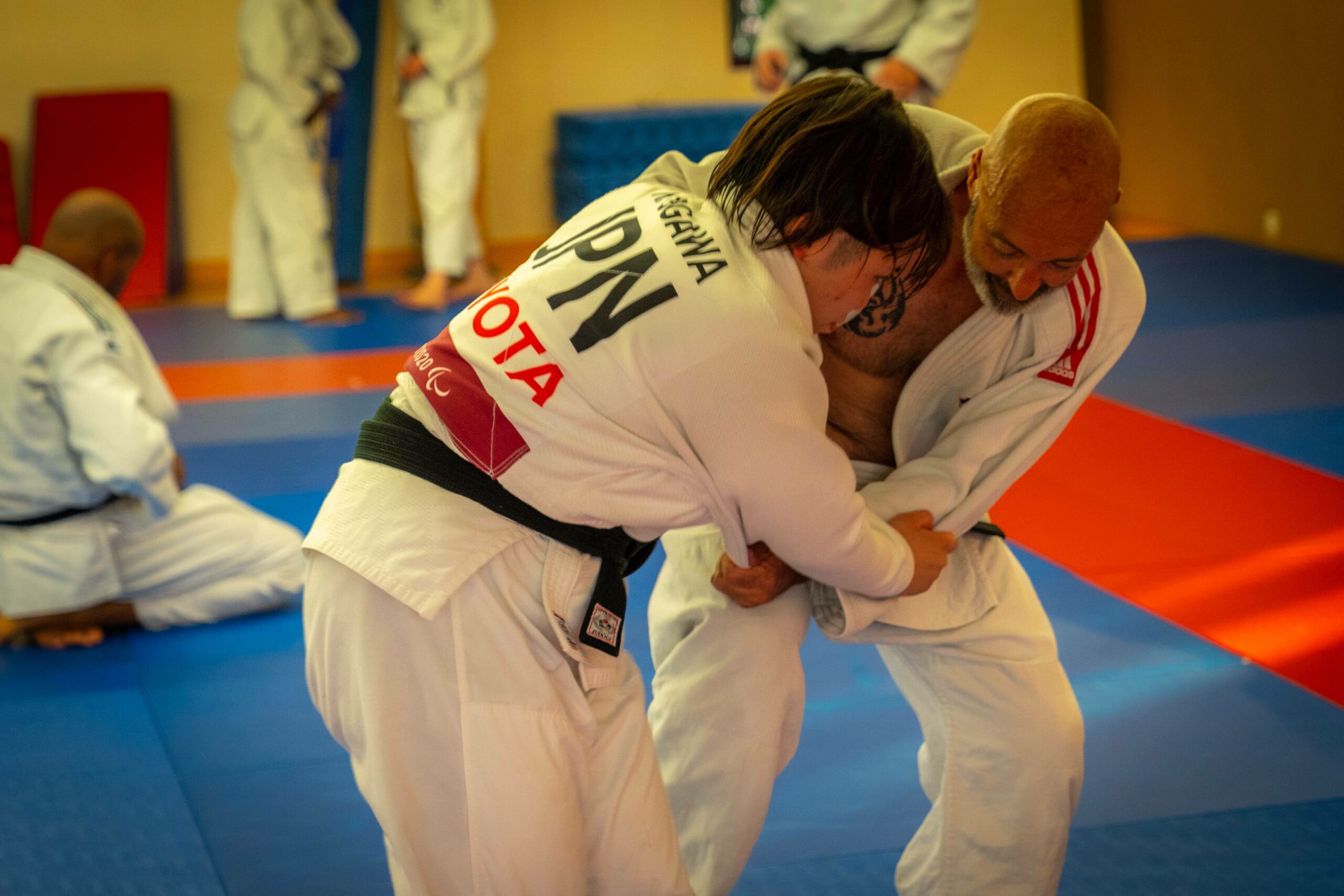 Judoka paralympique engageant un adversaire pendant un exercice debout.