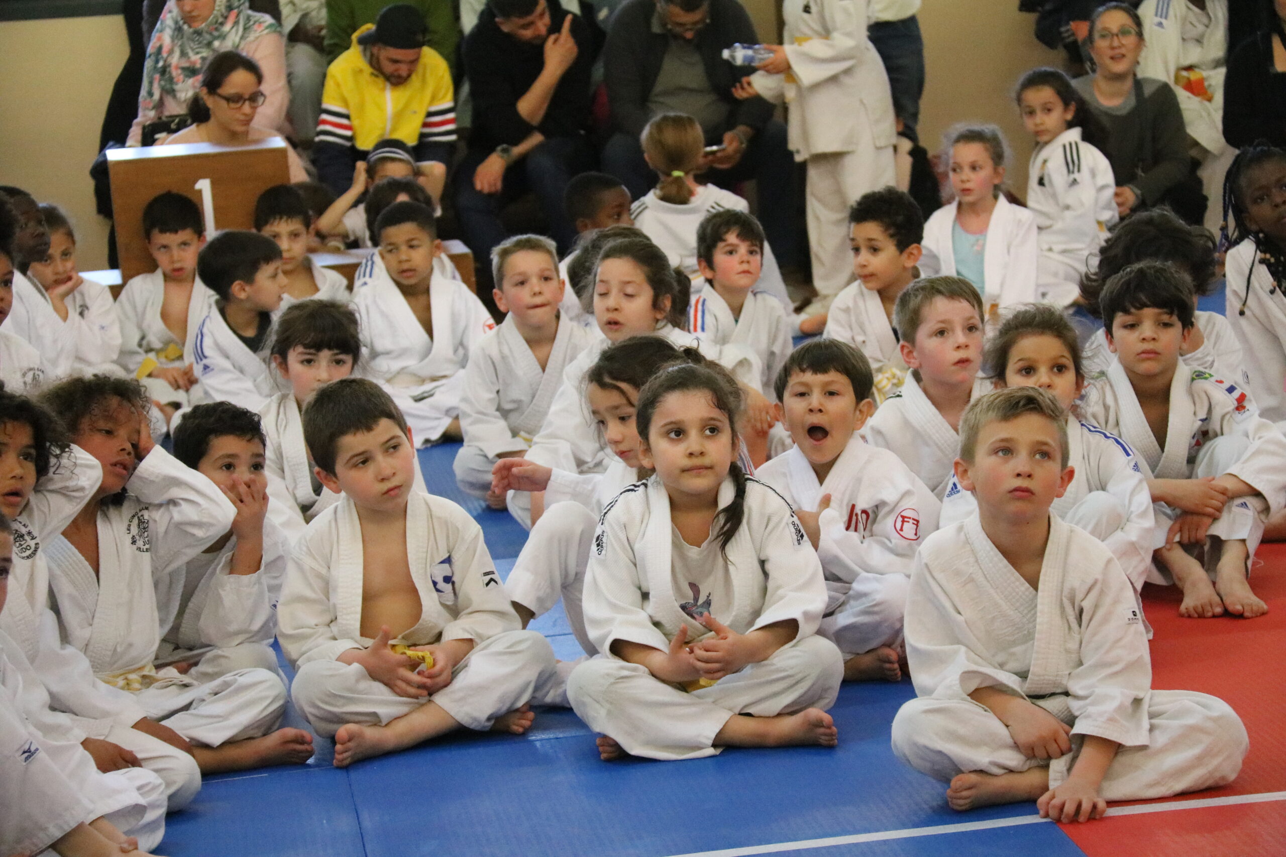 Enfants judokas assis en attente pendant une compétition ou une démonstration au club.