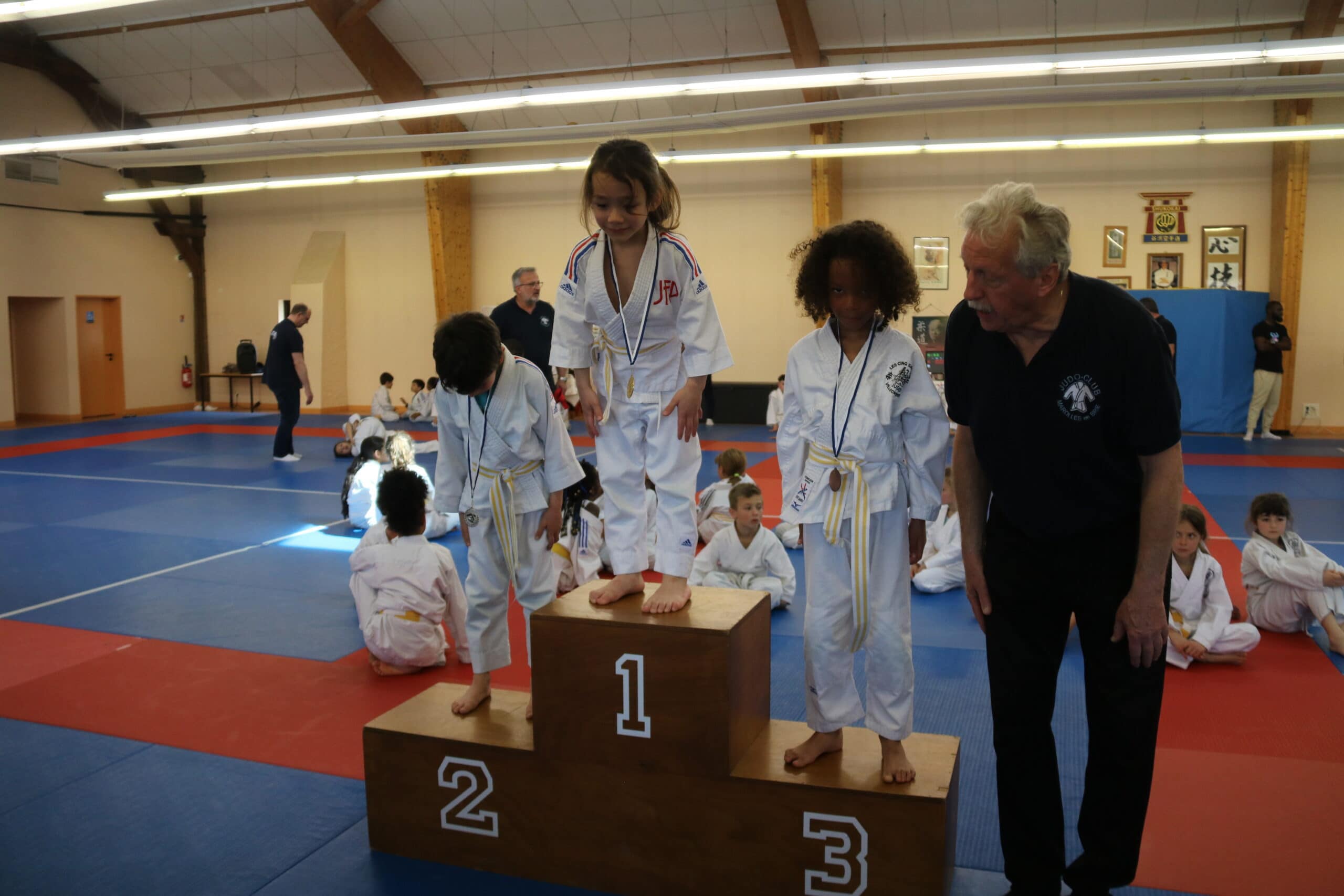 Jeune judoka debout sur le podium, souriant après avoir reçu la médaille d'or.