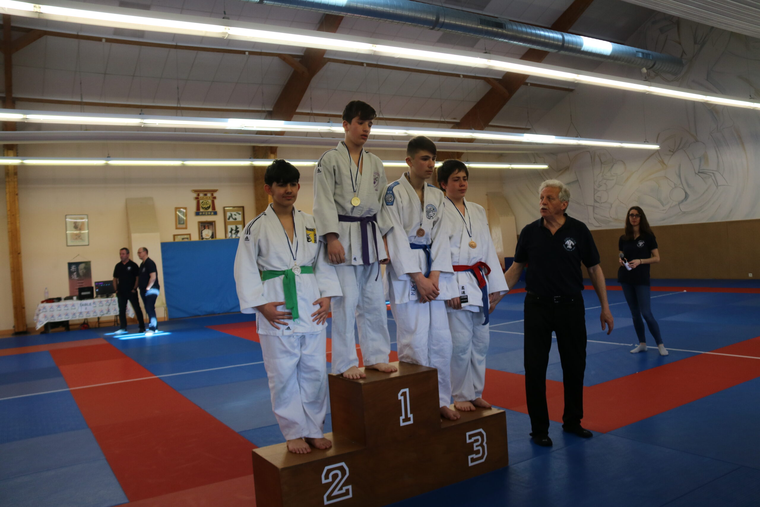 Podium de judokas adolescents avec leurs médailles, lors d'un tournoi au dojo.