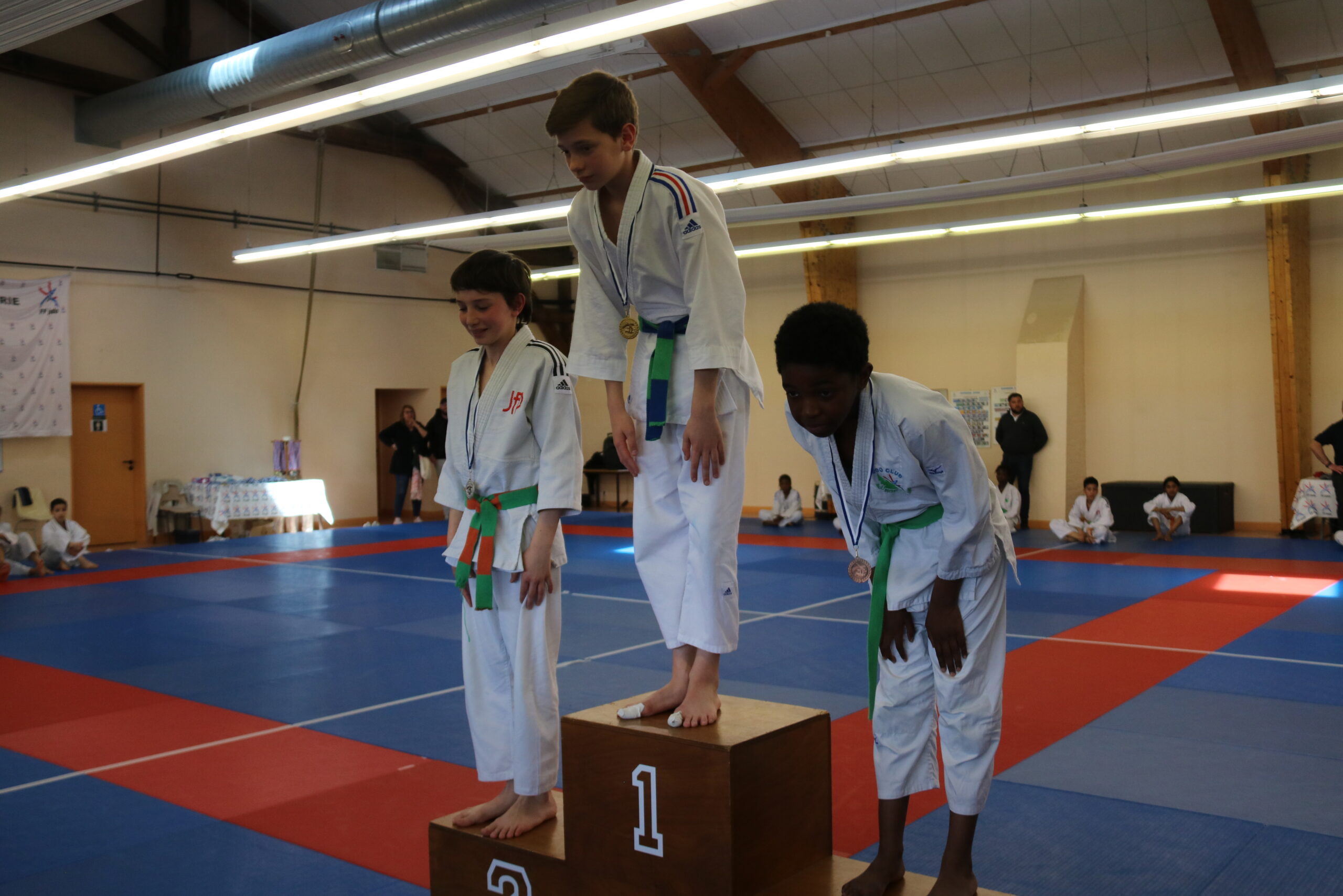 Trois judokas sur le podium, montrant fièrement leurs médailles après une victoire dans un tournoi.