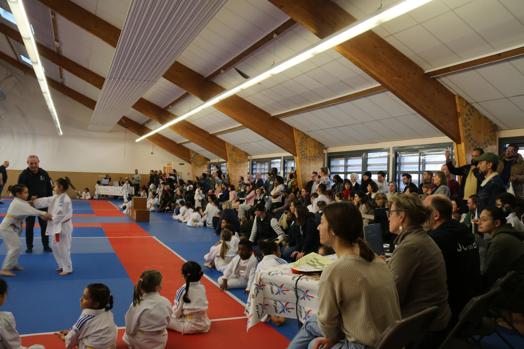 Jeunes judokas en ceinture blanche alignés pour une photo de groupe, exprimant leur enthousiasme.