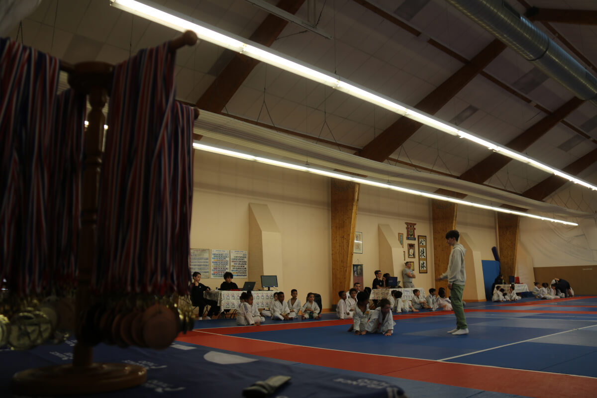 Groupe d'enfants judokas posant fièrement avec leurs ceintures jaunes et blanches après l'entraînement.