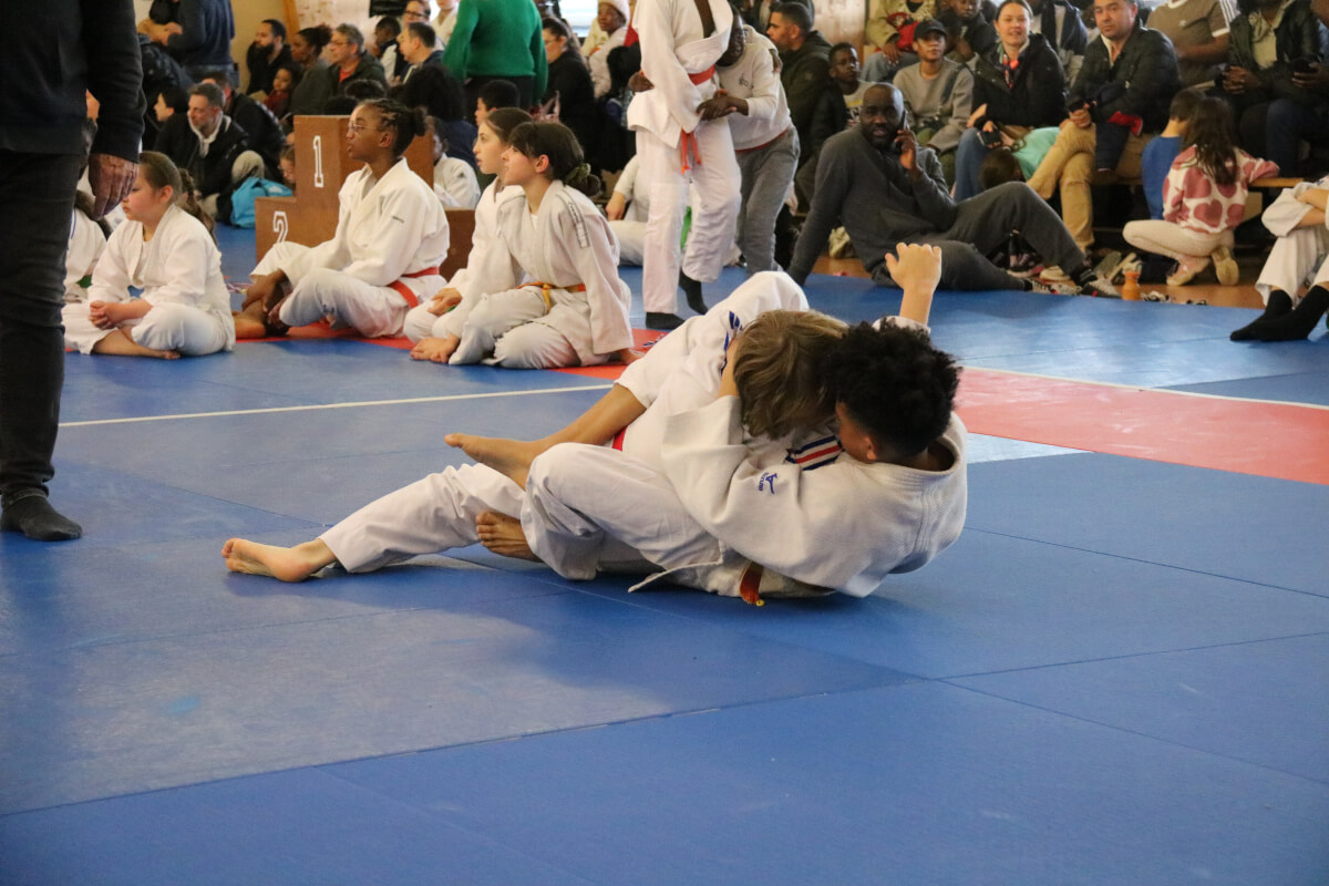 Deux petites judokas s'affrontant avec détermination lors d'un tournoi.