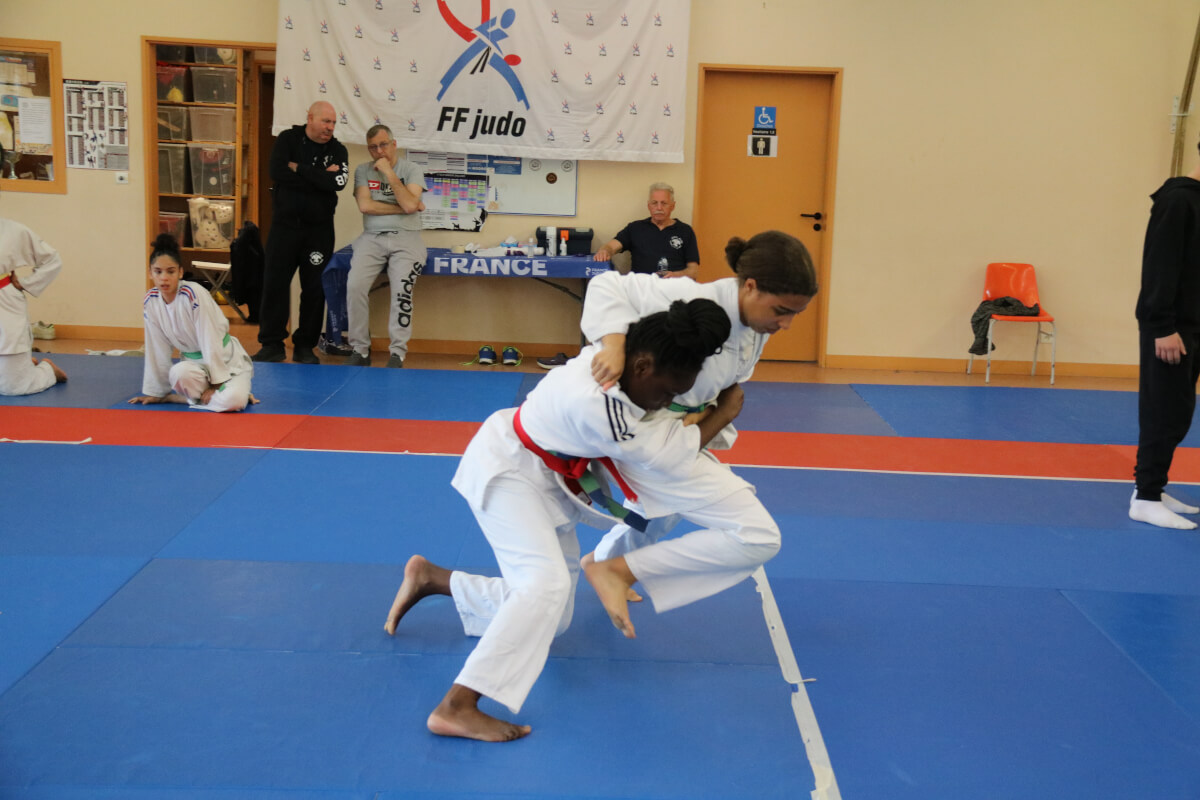 Quatre jeunes judokas fiers de leurs médailles, posant sur le podium après une compétition.