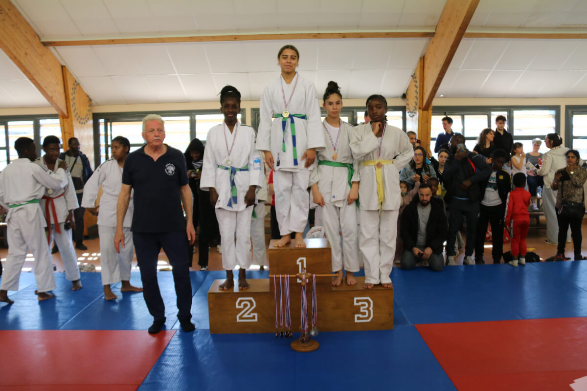 Jeune judoka debout sur le podium, souriant après avoir reçu la médaille d'or.
