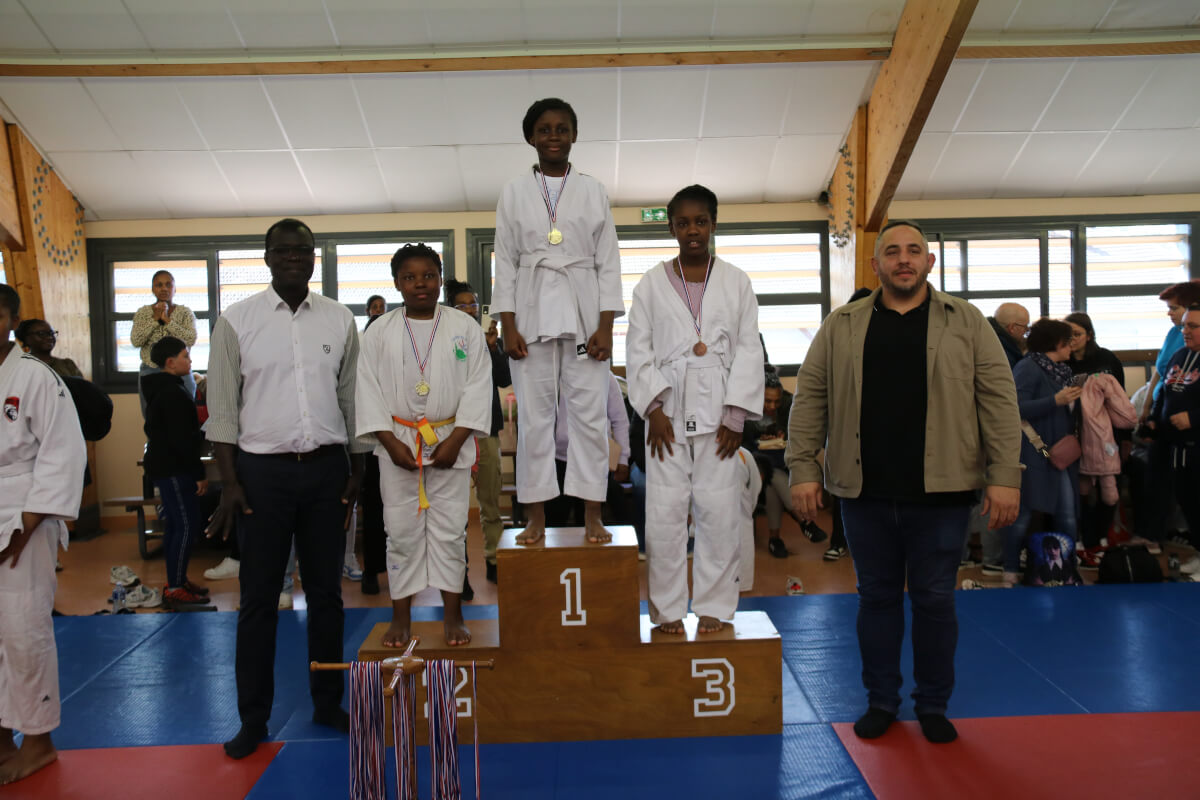 Podium de judokas adolescents avec leurs médailles, lors d'un tournoi au dojo.
